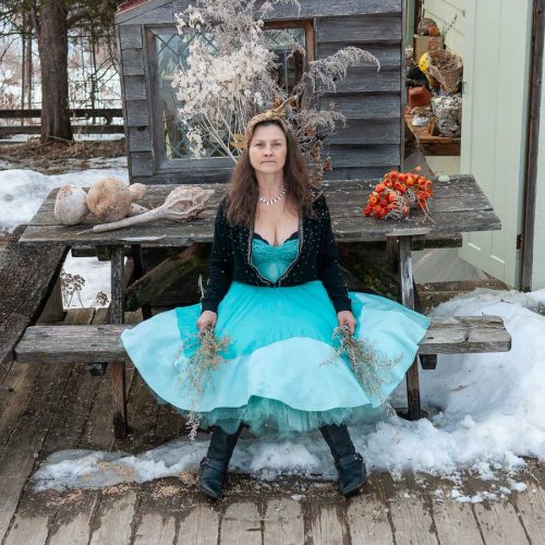 Woman in a turquoise dress sitting on a picnic table in the snow Iowa