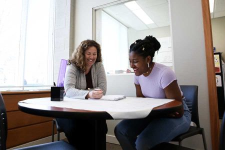 student and staff member work at a table