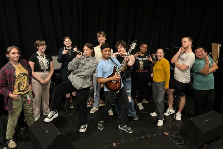 Members of the Pop/Contemporary Ensemble strike a fun pose with instruments at a rehearsal.