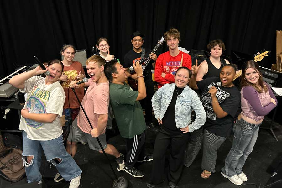 Members of the Pop/Contemporary Ensemble strike a fun pose with instruments at a rehearsal.