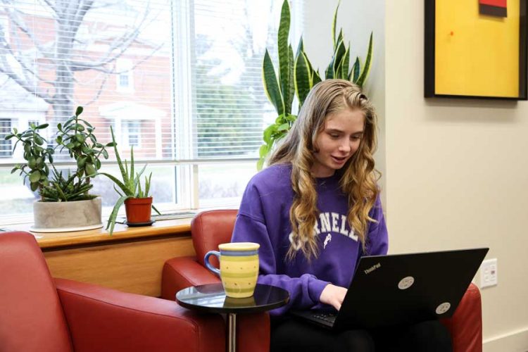 Student uses her laptop seated in a soft chair with coffee