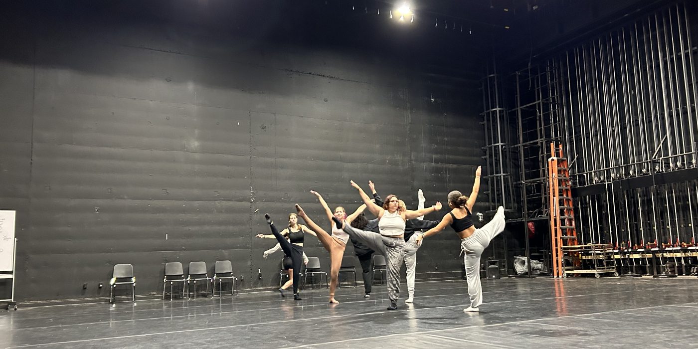 Several dancers hold a pose during a dance rehearsal.