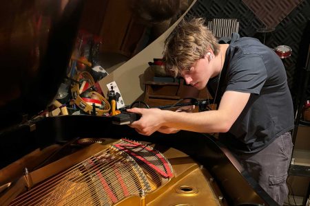 Lewis Fawcett ’26 places microphones in a Steinway grand before recording a piece he had been working on during his internship at a recording studio in New York. Photo by Dave Cook.