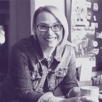 Liz Bennett '10 in jeans jacket with coffee cup, black and white