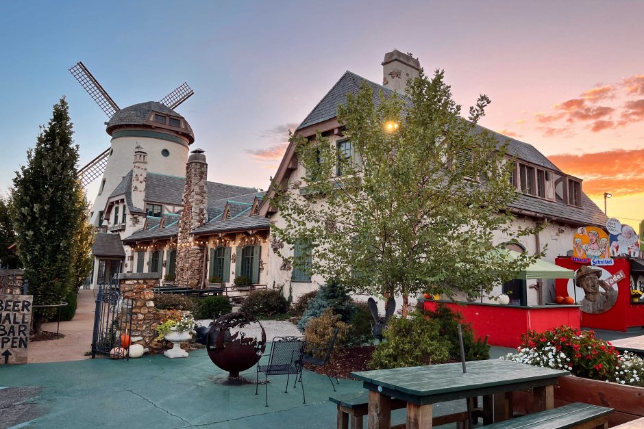 A German-style building with a windmill and the sunsetting in the background.