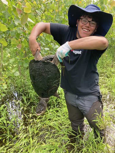 Jason Ramos ’25 holds a large snapping turtle by the legs. 